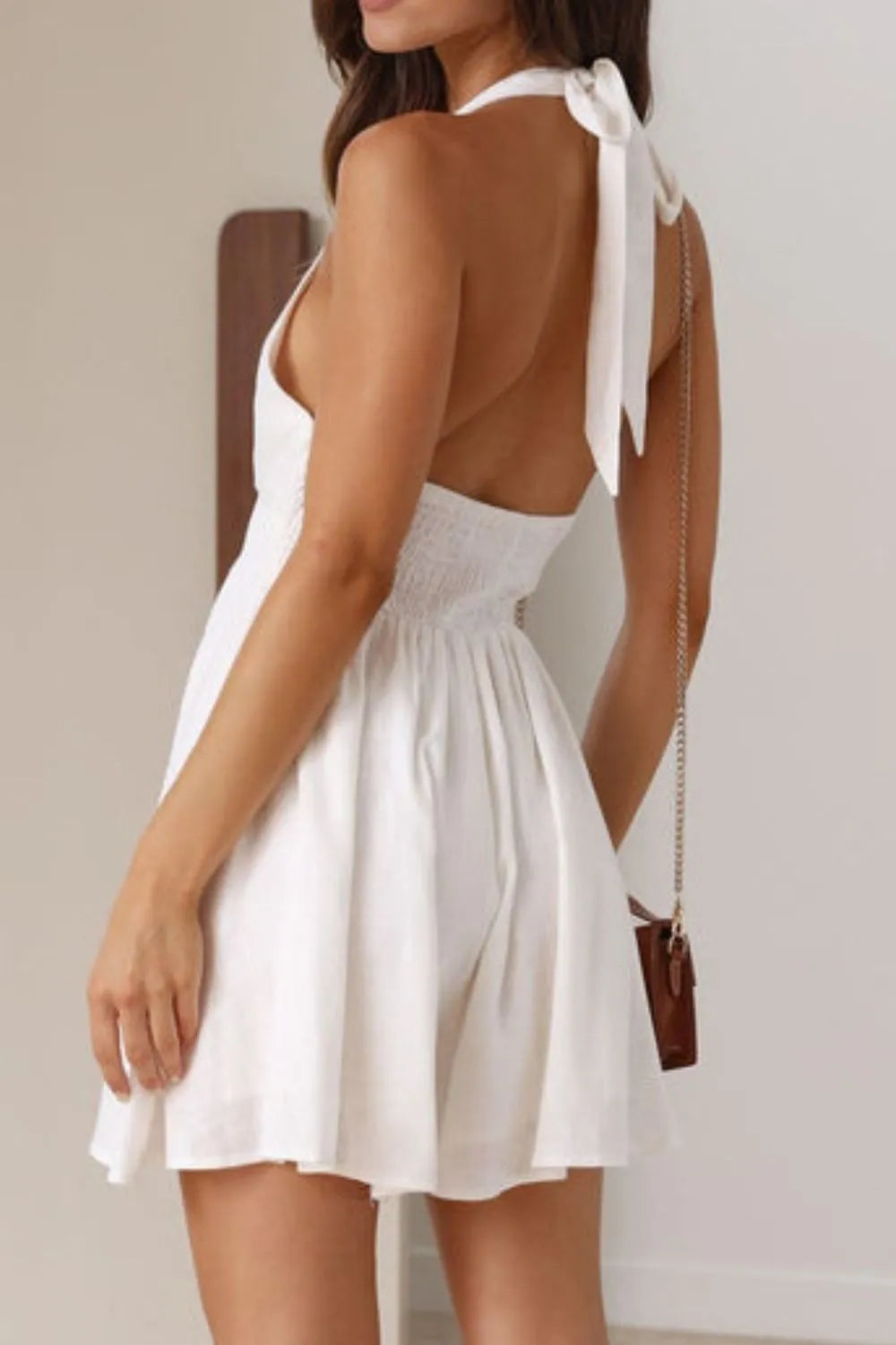 Woman wearing a white dress with a backless design and tied straps.